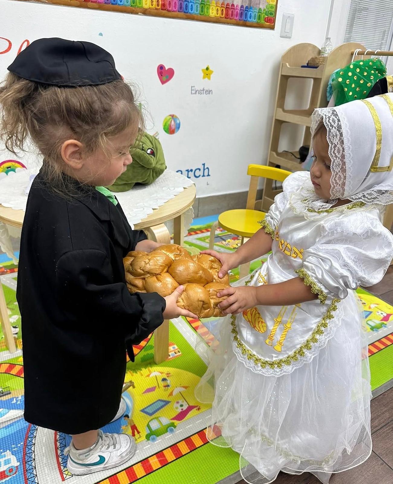 Two children sharing challah for Shabbat